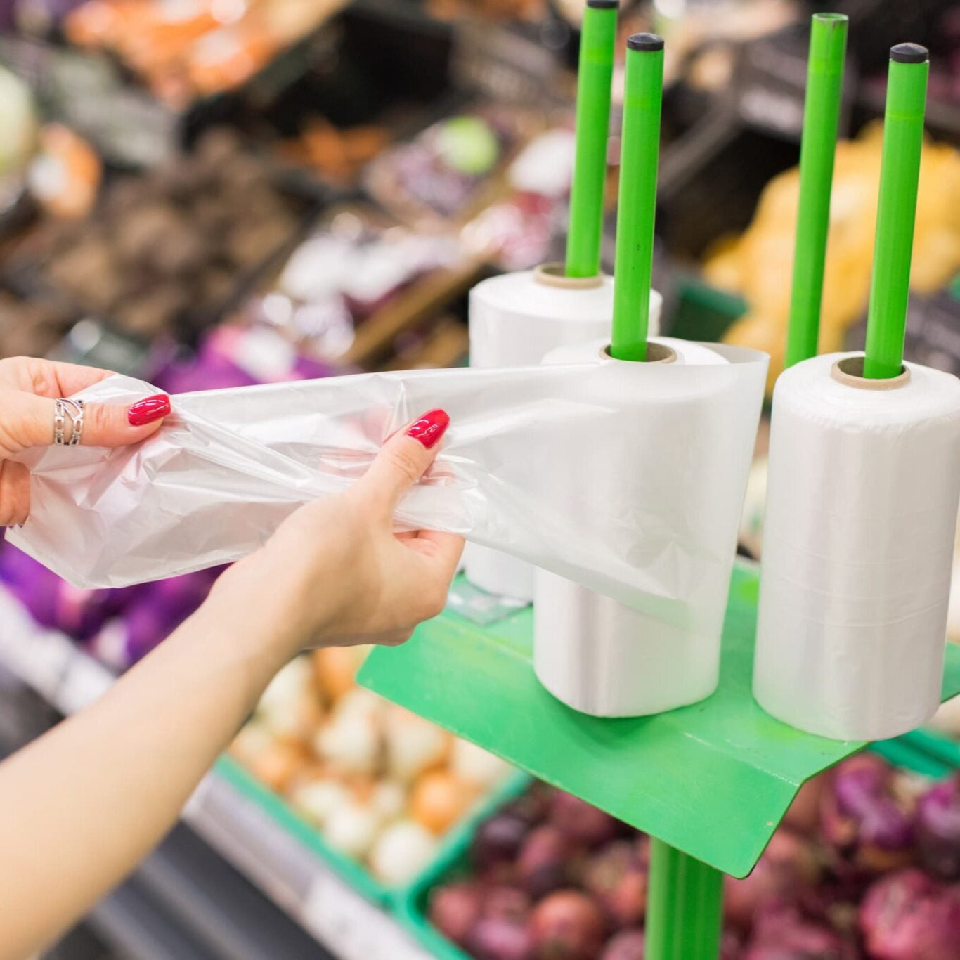 Customer taking a piece of plastic bag in the supermarket to store picked fruits.