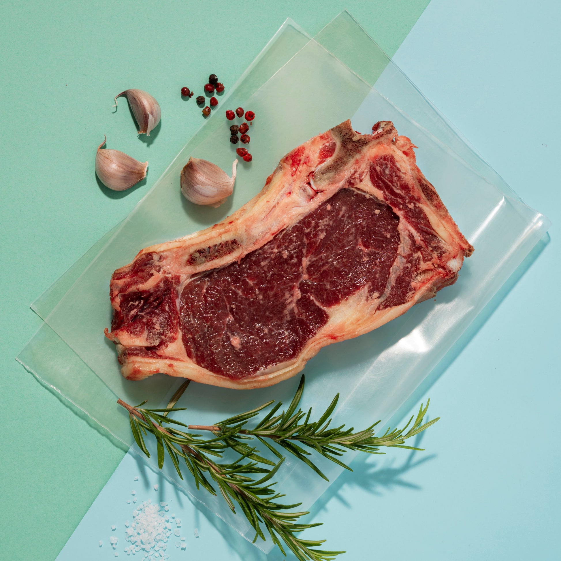 A piece of fresh meat displayed in a clear polyethylene plastic bag with spices around it.
